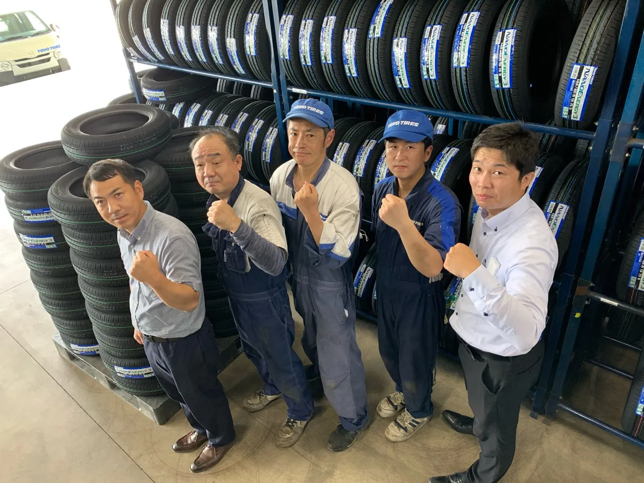 タイヤのラックの前でこぶしを握る社員