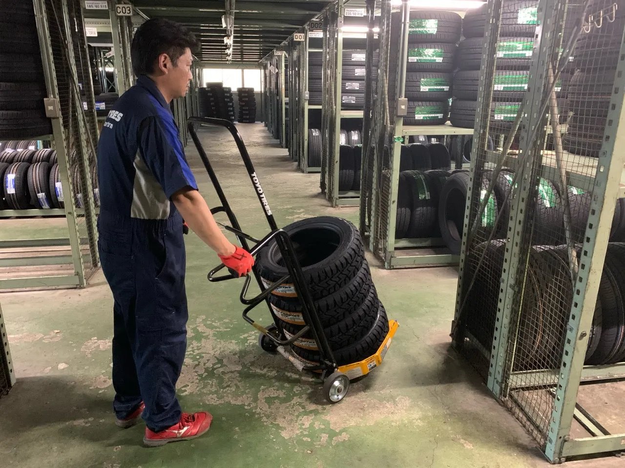 倉庫でタイヤを台車で運ぶ社員
